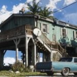 The Key Lento beach house in GTA 6, with Jason on the roof, fixing leaks.
