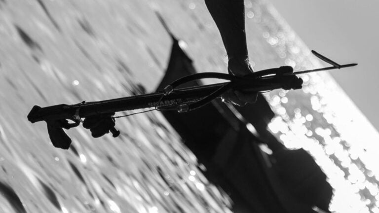 A photo of a speargun being held in a man's hand.